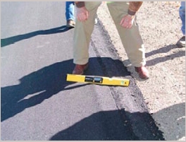 Photo of a level resting on a newly installed Safety Edge, demonstrating the acceptable slope of 29 to 40 degrees at the paved edge.