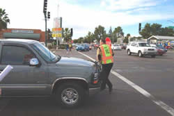 A crossing guard with stop sign walks past a truck that has stopped after crossing over into the pedestrian crosswalk.