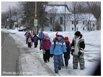 Photo of a group of elementary school students and two adult escorts walking to school. Photo by J. Corrigan.