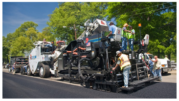 A construction crew conducts paving operations on a roadway