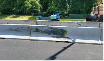 A concrete jersey barrier with skid marks marring the surface.