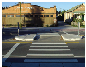 A pedestrian refuge island offers a protected place for pedestrians to wait for a safe gap in traffic to complete their crossing.