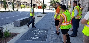 Photo shows participants in fluorescent vests looking at a bike lane.
