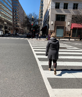A pedestrian enters a crosswalk while the light for through traffic remains red, allowing her to establish her presence in the street.