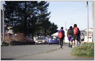 Photo shows students walking along the side of a rural road.