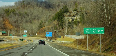 Photo shows car driving on two-lane road with a sign indicating an upcoming intersection at Little Coal River Road.