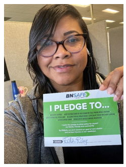 A woman holds up a pledge card with her signature on it.