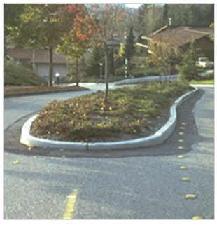 Figure 7 (top).  Two pictures showing curb treatments.  The picture on top shows a vertical curb around a median island; the picture on the bottom shows a sloping curb around a median island.