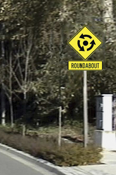 Figure 82. A picture of an approach to a roundabout with an experimental advance roundabout warning sign superimposed on the roadside in the picture.