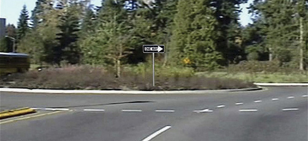 Figure 84. A picture of an approach to a roundabout with a 'ONE WAY' sign superimposed on the roundabout central island in the picture.