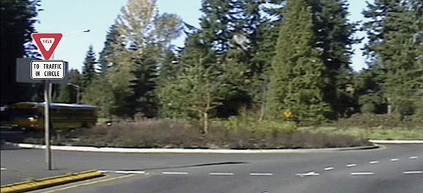 Figure 85. A picture of an approach to a roundabout with a 'YIELD' sign and 'TO TRAFFIC IN CIRCLE' plaque superimposed on the splitter island in the picture.