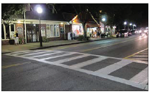 Image shows a crosswalk marked with a high-visibility ladder pattern