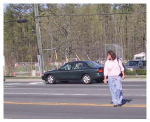 Photo of a woman walking across a street with no crosswalk in a mid-block area.