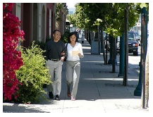 Photo of a couple strolling down an urban sidewalk.