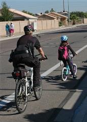 A police officer and a child riding their the bikes in a marked bike lane