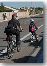 Photo: A police officer rides in a bike lane with a child cyclist.