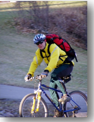 Photo: Male cyclist with red backpack looks at camera.