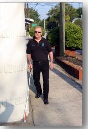 Photo: Pedestrian who is visually impaired navigates around a column with a white cane.