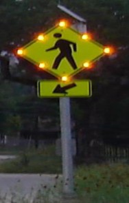 Photo:Pedestrian crossing warning sign outlined with flashing lights.