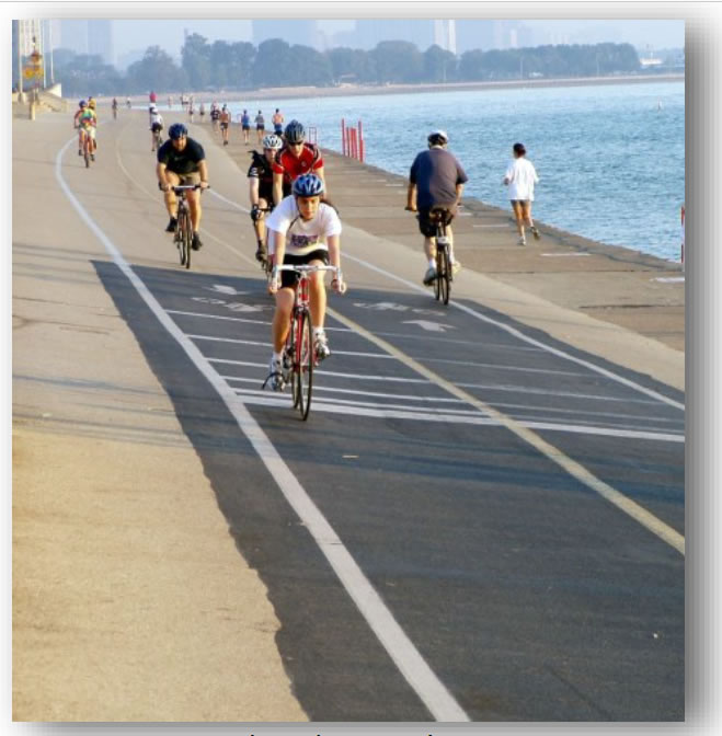 Bike lanes with bikers next to water.