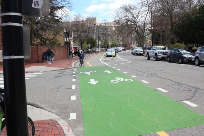 A one way street with a two-way bicycle lane. Green paint is applied to the bicycle lane where it intersects with an intersection.