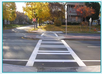 Photo of a crosswalk in a suburban neighborhood that uses a channelized median as a pedestrian refuge.