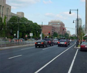 Photo.  A multilane urban roadway with a bike lane in between the far right travel lane and on-street parking.  A curb bulb-out extends into the bicycle lane.
