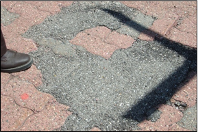 Figure 29: Damaged pavers have been repaired with asphalt to alleviate a hazard.