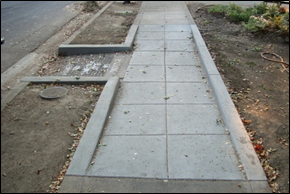 Image 1: A concrete sidewalk and curb ramp
