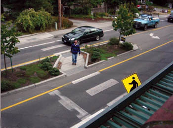 Man waiting to cross the street in angled cut-through in raised median