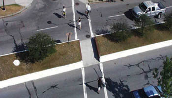 Pedestrians crossing street through a cut-through in the raised median