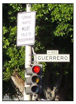 Photo of a sign mounted next to a signal head indicating turning traffic must yield to pedestrians.