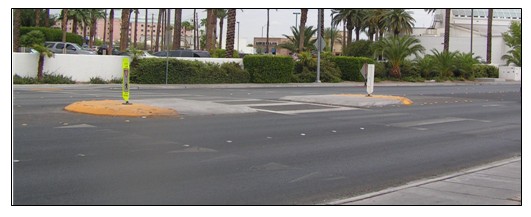 Photo of a refuge island at a mid-block crossing in which a median has been added for the sole purpose of providing a pedestrian refuge across a multi-lane roadway where no signal is present.