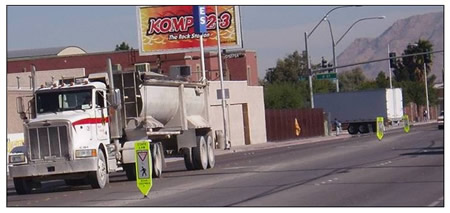 Photo of a truck in a travel lane where in-street pedestrian signs are mounted on the center line.