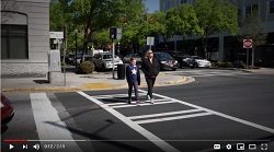Screenshot of video shows two people using a crosswalk.