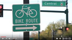 Screenshot of video shows a bike route road sign with an arrow pointing right.