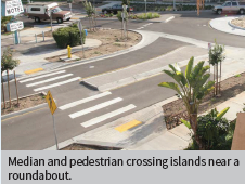 Median and pedestrian crossing islands near a roundabout.