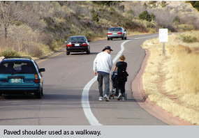 Pedestrians use a paved shoulder as a walkway.