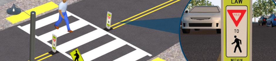 A person is crossing the street at a marked pedestrian crosswalk. There are additional markers and signs strategically positioned for increased pedestrian visibility by vehicular traffic.