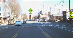 A post-treatment intersection contains a crosswalk and pedestrian refuge island.