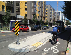 Bus loading zone on a raised median separates a dedicated bike lane from a side walk in Seattle.