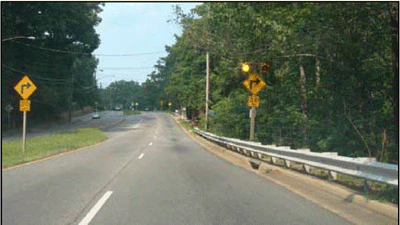 Photographs showing a four-lane roadway where doubled turning signs are used. One horizontal curve warning sign is installed on the right side and supplemented with flashing beacons. However, the sign is partially blocked by tree limbs. As a result, a second, identical sign is installed on the median, which is on the left side of the roadway.