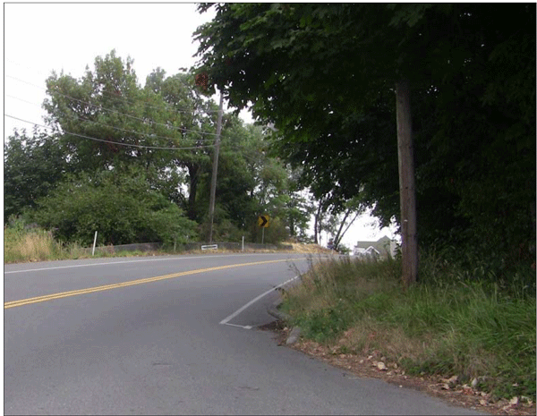 Photograph of a three-leg intersection on a two-lane roadway with limited sight distance due to the intersection being inside the curve.