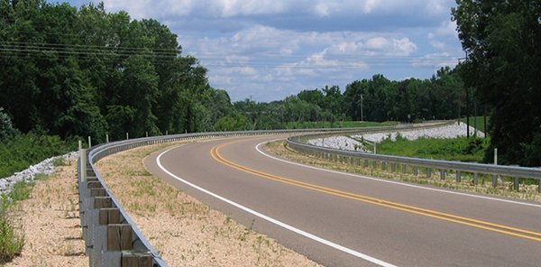 Figure 1.  Photo.  Example of longitudinal barrier.  This photo of a two-lane country road shows a longitudinal barrier along both sides of the curve.