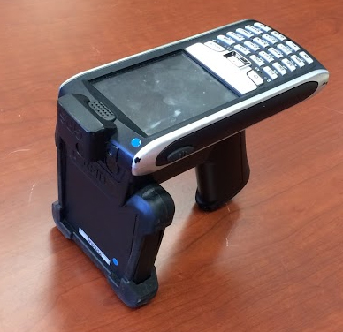 Figure 9.  Photo.  Handheld RFID reader.  This photo shows a handheld radio frequency identification reader. The reader has a screen, keypad, and grip handle.