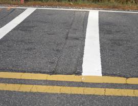 Photo.   Close up view of RRS placed 200 ft prior to a curve on a 2 lane roadway.  There are 5 sets of lines and grooves that transverse the lane which approaches the curve.