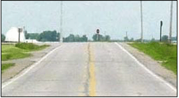 Photograph of a two-lane roadway without chevrons within the curved section.