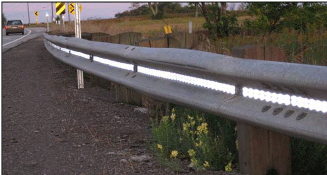 Close-up photograph of a section of W-beam with retroreflective panels in the web.