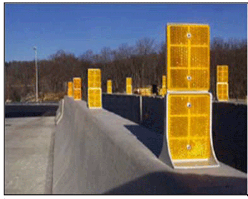 Close-up photograph of yellow reflective delineators installed on top of concrete barriers.