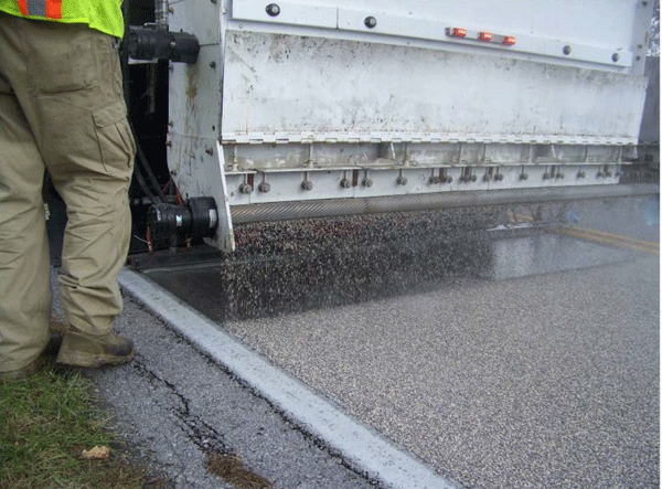 Close-up photograph of the processing part of a truck that is applying HFST to a curve.